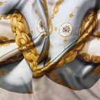 Mlle Ceinté Paris 100% silk twill scarf, gold chain knot design on beige, hand-rolled hem detail.