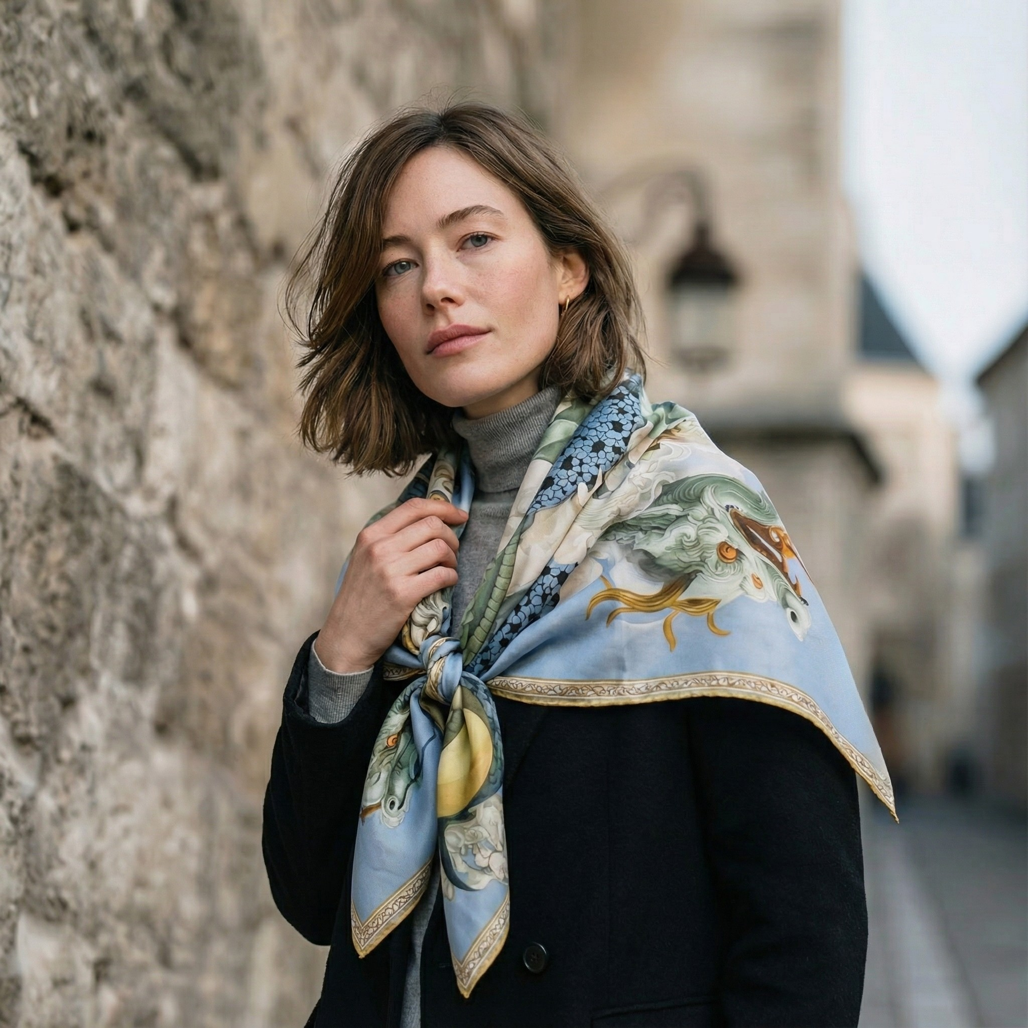 Mlle Ceinté Paris silk scarf, blue scaled dragon intertwining with classical marble statues, sky blue background with orange accents, hand-rolled hem.