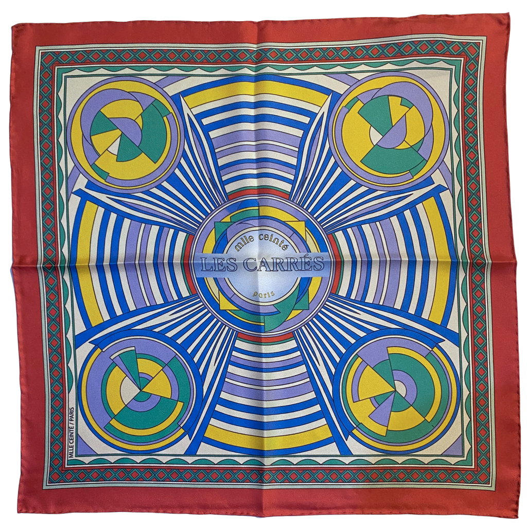 Mlle Ceinté Paris ipek eşarp, merkezden yayılan hipnotik çizgiler, sarı mavi ve yeşil geometrik daireler, kalın kırmızı bordürlü lüks şal. Mlle Ceinté Paris silk scarf, bold red border, hypnotic radiating lines with yellow, blue and green geometric circles, luxury square.