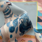 Mlle Ceinté Paris ipek eşarp, merkezde mavi beyaz porselen desenli aristokrat tazı figürü, pastel pembe zemin üzerinde romantik çiçekler ve neon yeşil şeritli lüks şal.
Mlle Ceinté Paris silk scarf, central aristocratic hound figure with blue and white porcelain pattern, surrounded by romantic flowers on a powder pink background with neon green border.
