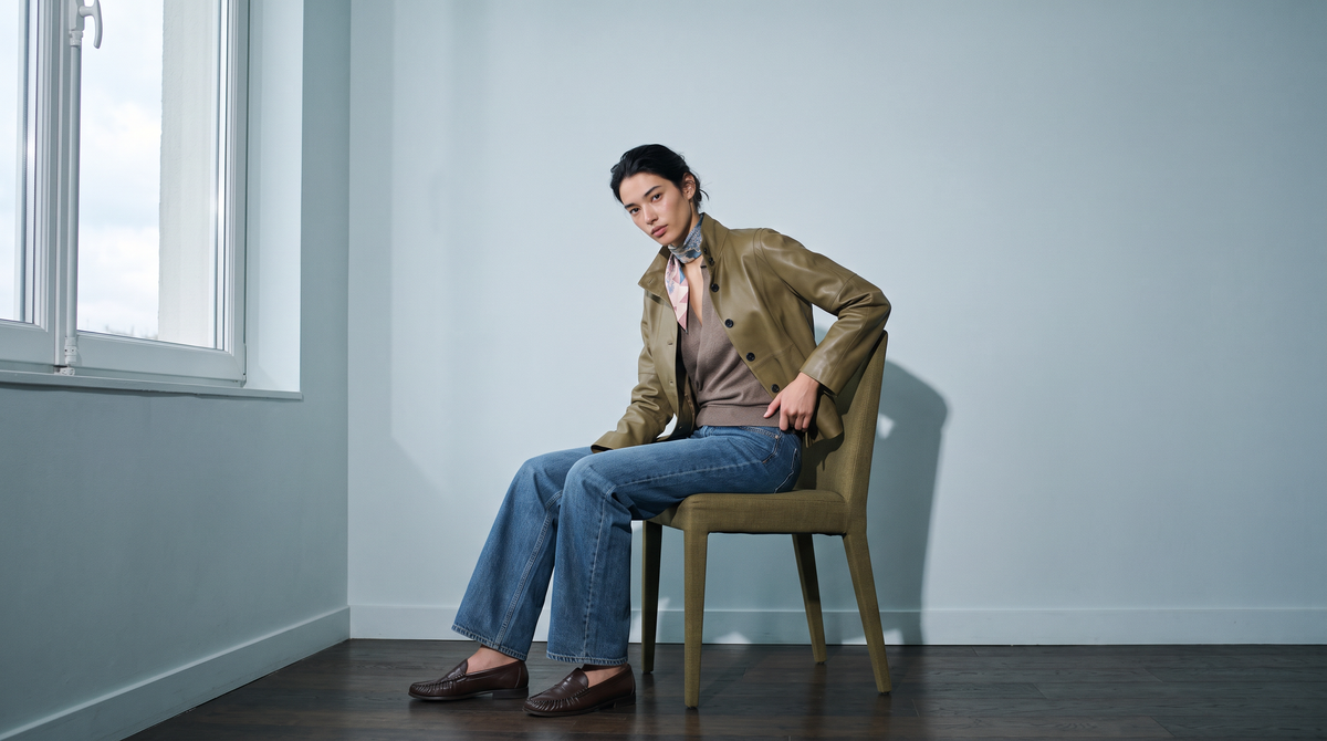 The Porcelain Hound silk carré tied at the neck, worn with a leather jacket beside a window.