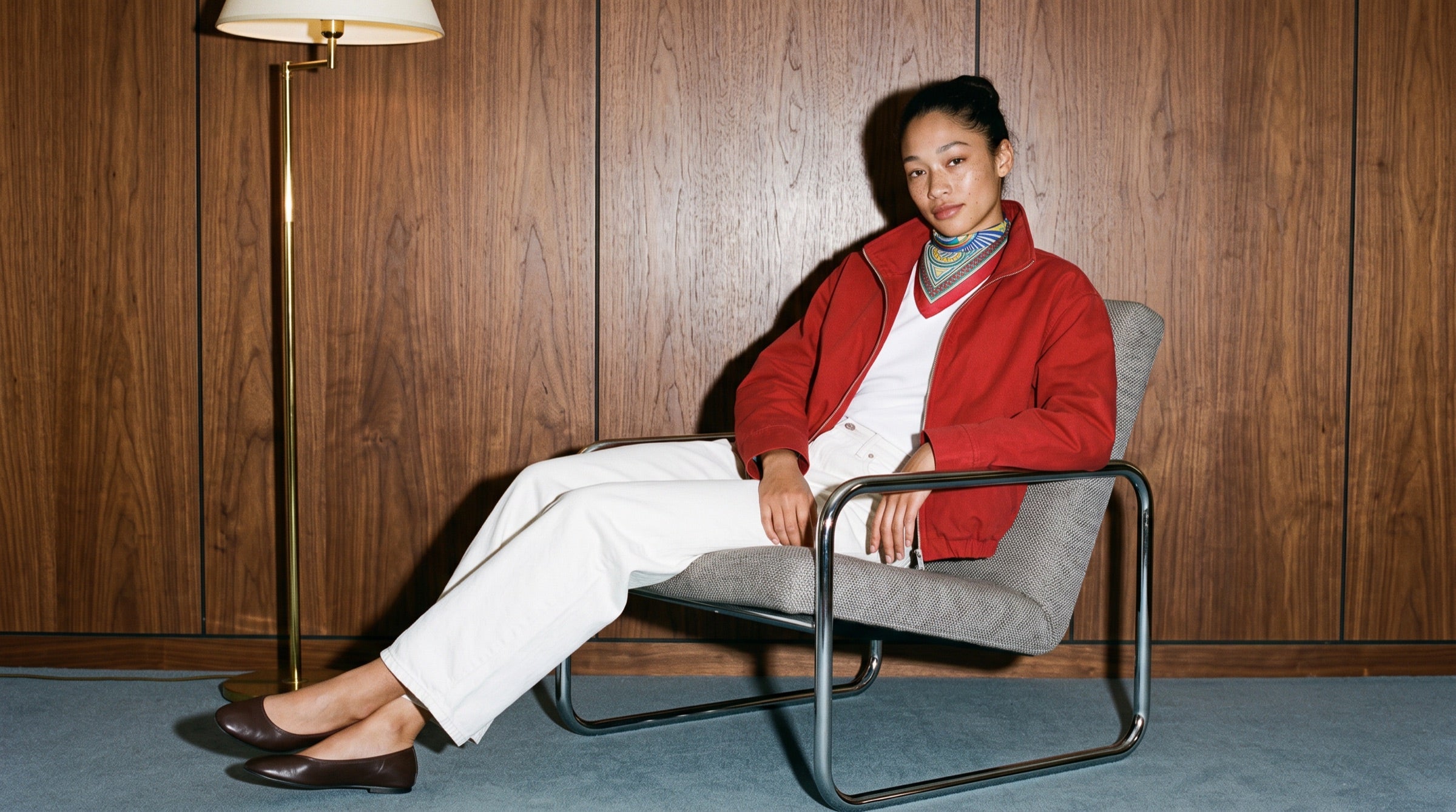 The Optical Symphony silk carré worn with a red jacket in a wood-panelled room.